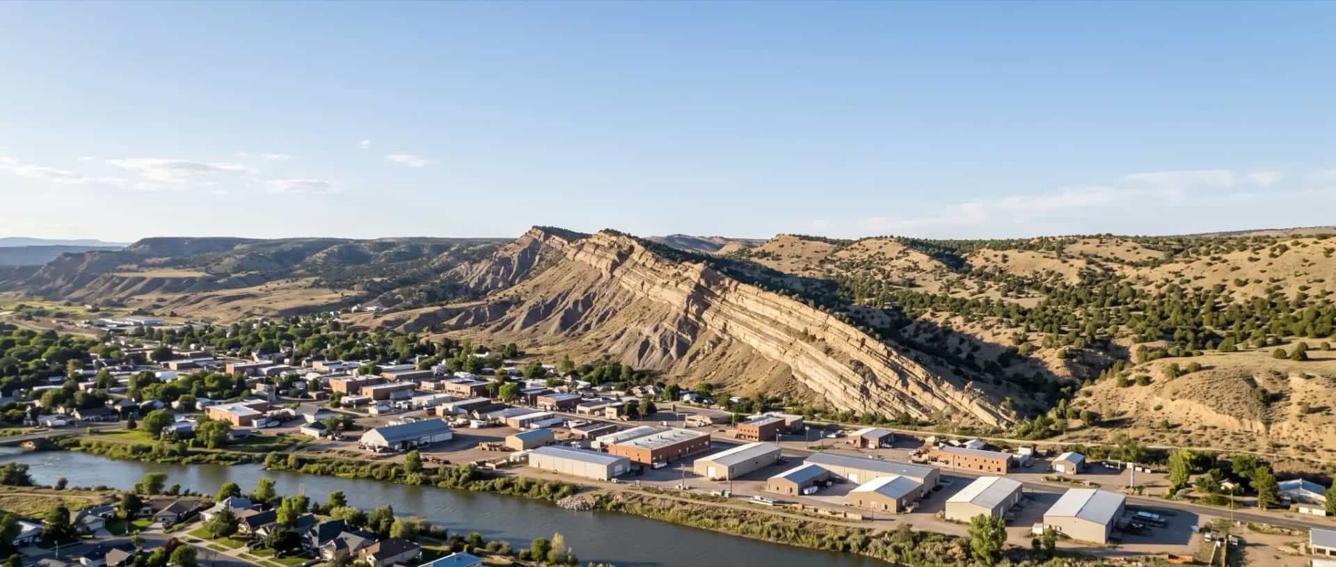 Illustrative representation of rooftops on the Colorado River valley floor at Rifle, Colorado beneath the tilted rock of the Grand Hogback