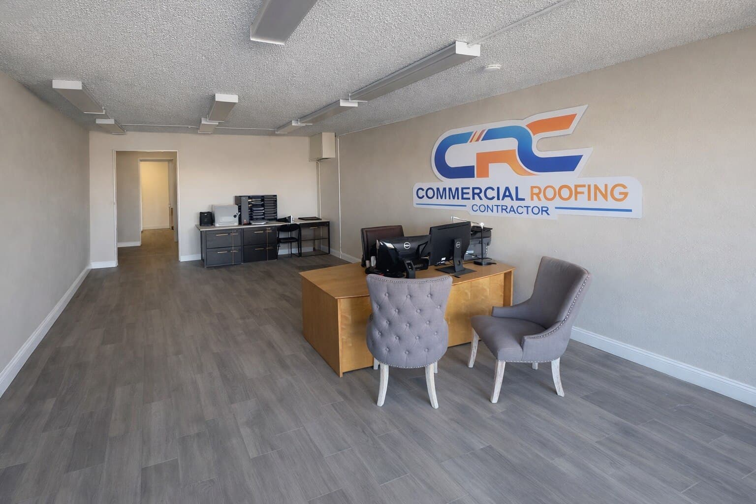 The reception area inside the Commercial Roofing Contractor office in Grand Junction, Colorado, with the CRC logo on the wall behind the desk