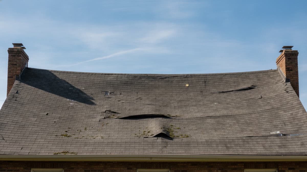 Illustrative representation of a house roof with a visibly sagging, dipping roofline indicating a structural problem